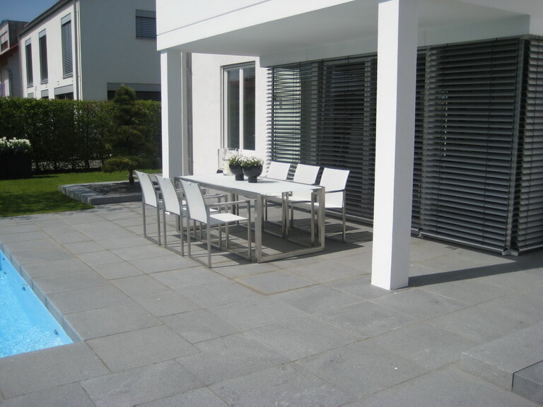 Dunkle Escura Granitplatten als Terrassen- und Poolumrandung, modern verlegt.