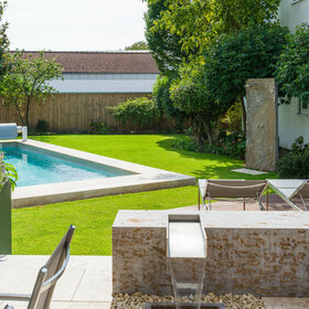 Garten mit Pool, Poolrandplatten, Wasserspiel aus Muschelkalk und Outdoor-Dusche aus Krustenplatte.