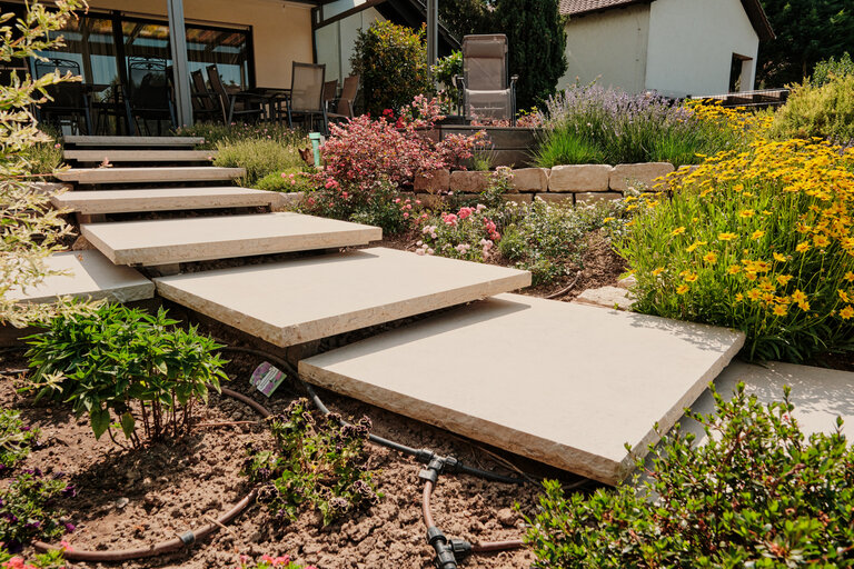Schwebstufen aus Kanfanar Kalkstein als Podeststufen zwischen Terrasse und Garten.