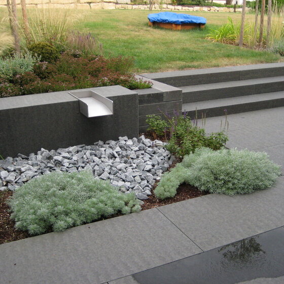 Masaya Bodenplatten in harmonischer Gartenumgebung mit Pflanzen und Natursteinelementen.