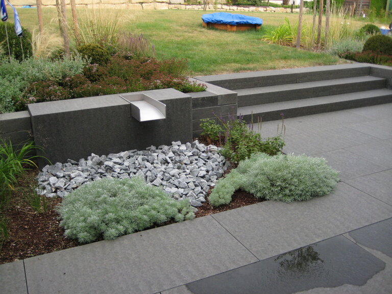 Masaya Bodenplatten in harmonischer Gartenumgebung mit Pflanzen und Natursteinelementen.