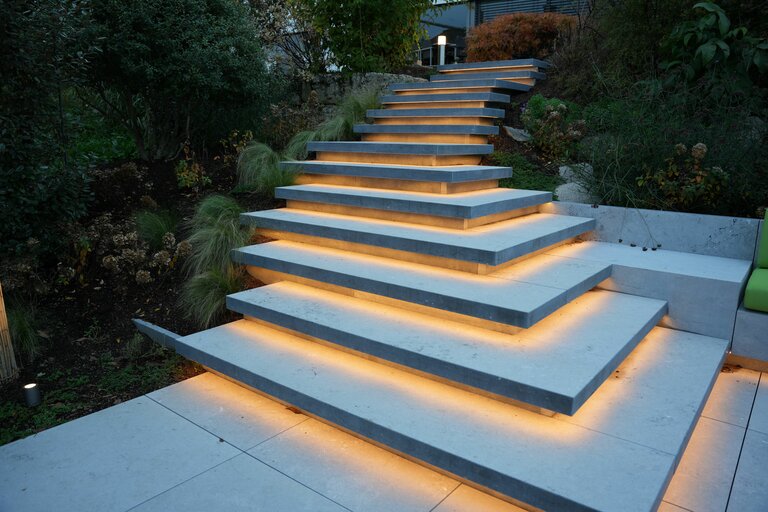 Schwebstufen aus Belgisch Blau Naturstein mit LED-Unterleuchtung für moderne Treppen