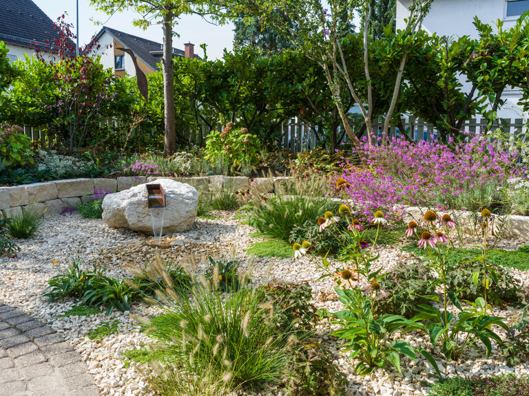 Mediterraner Garten mit Findling, Kiesflächen und Bepflanzung Weitwinkelansicht des Gartens mit Findling, mediterraner Bepflanzung und Kies.