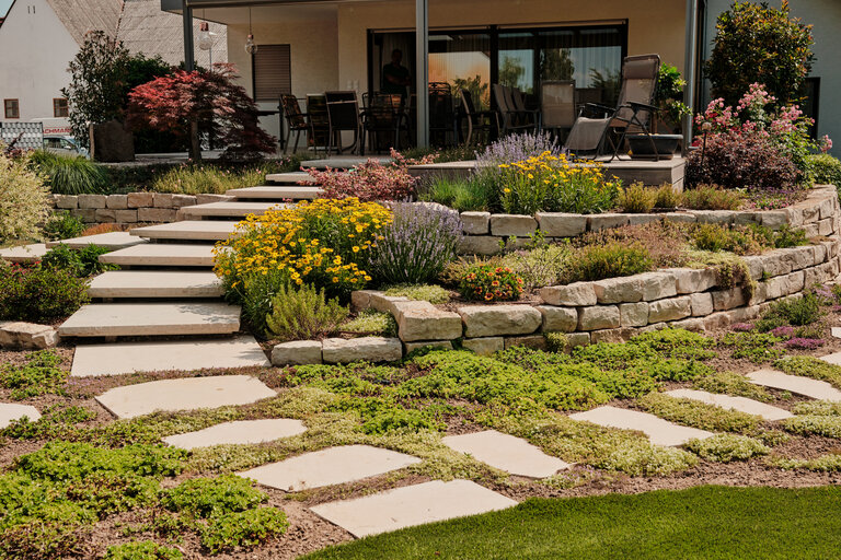 Garten mit Schwebstufen, Hochbeet und Trittplatten aus Naturstein Garten mit Schwebstufen, Hochbeet aus Muschelkalkmauersteinen und Trittplatten.