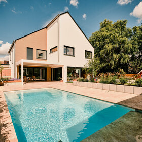 Pool mit Boden- und Poolrandplatten aus Finca Beige Travertin in mediterranem Garten.